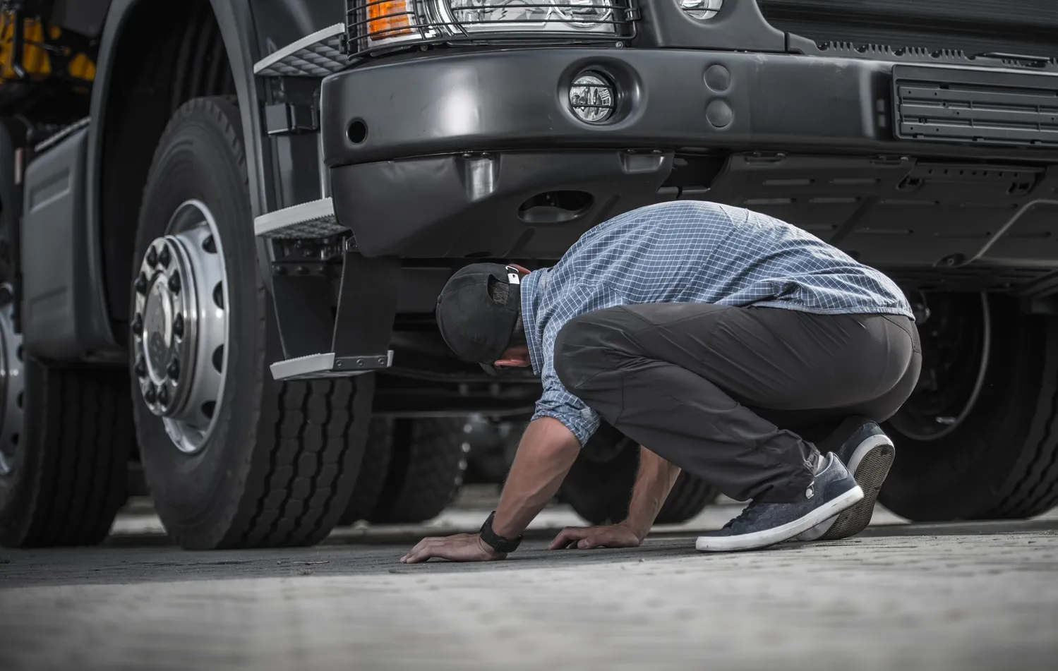 man performing semi truck roadside assistance inspectioning a semi truck